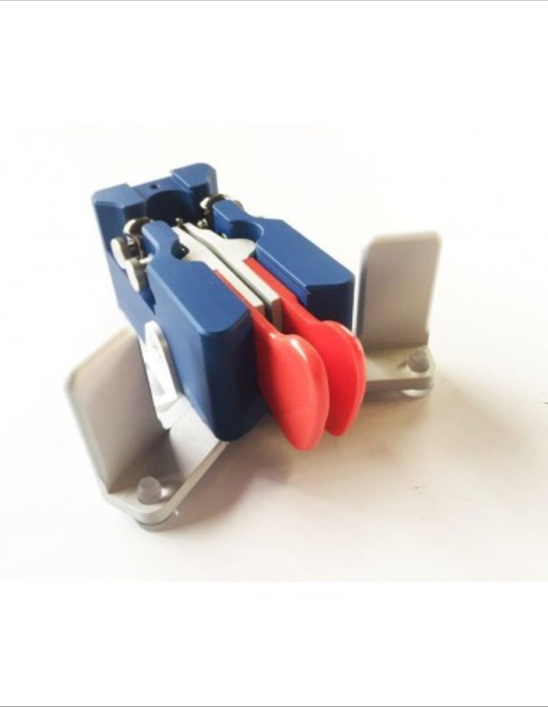 photo of a Begali Traveler Light morse iambic paddle key. The body is a dark blue and the finger pads are orangey-red. An iambic paddle has two levers - pressing the left one with the thumb provides a stream of dashes, and the left one provides dots. Pinching both makes an alternating stream of dots and dashes.